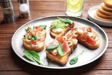 Tasty bruschettas with prosciutto and olives on plate