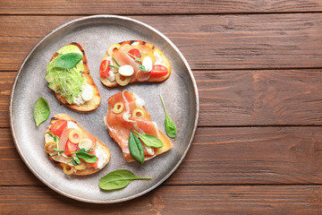 Tasty bruschettas with prosciutto and avocado on plate