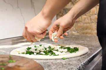 Chef making pizza at table in restaurant kitchen