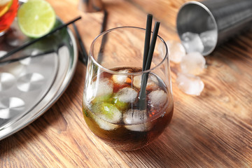 Glass of Cuba Libre cocktail on wooden table