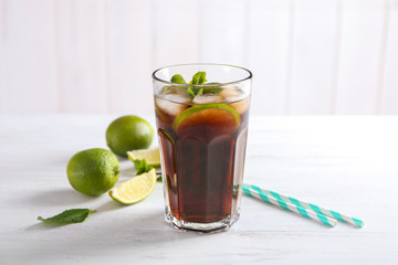 Glass of Cuba Libre cocktail on white wooden table