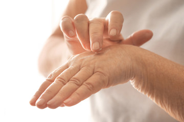 Senior woman applying hand cream, closeup