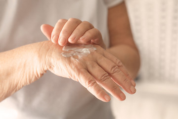 Senior woman applying hand cream, closeup