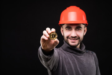 Handsome man miner in protective hemlet pointed bitcoin isolated on black background
