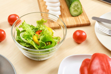 Bowl with fresh vegetable salad on table