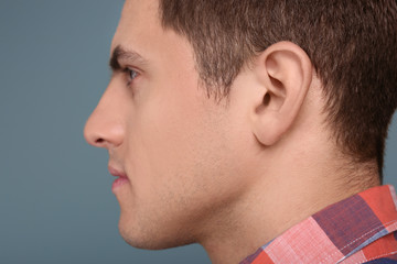 Young man on grey background. Hearing problem