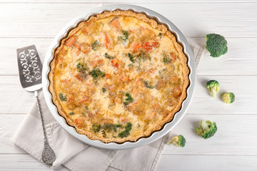 Baking dish with tasty broccoli quiche on table