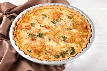 Baking dish with tasty broccoli quiche on table