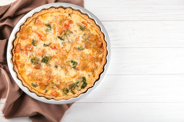 Baking dish with tasty broccoli quiche on table