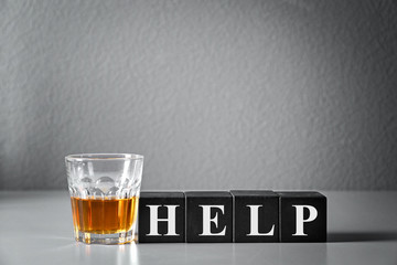 Strong drink and cubes with word HELP on table. Concept of alcoholism