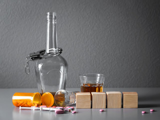 Strong drink, drugs, handcuffs and cubes with space for text on table. Concept of alcoholism