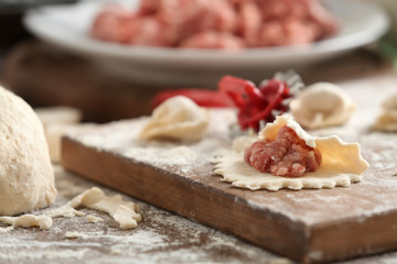 Raw dough with minced meat for dumpling on wooden board