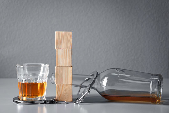 Strong drink, handcuffs and cubes with space for text on table. Concept of alcoholism