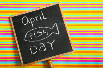 Chalkboard with phrase "April fish day" on color background