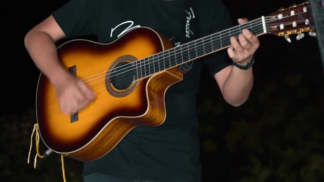 Close up of man hands playing yellow guitar at night