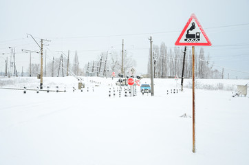Railway crossing without a barrier with a lot of warning signs in the snowy winter season