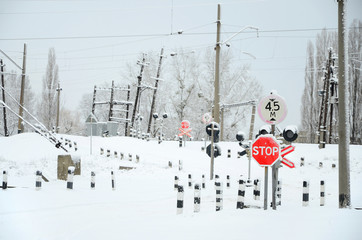 Railway crossing without a barrier with a lot of warning signs in the snowy winter season