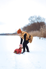 beautiful girl in a fur vest plays with a dog in the snow
