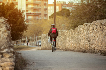 Cyclist pedaling his bike on a narrow street with stone wall and an old neighborhood