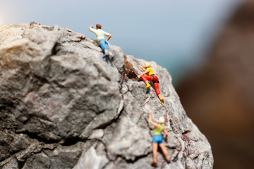 Miniature people: Climber looking up while climbing challenging route on cliff, Concept of the path to purpose and success.