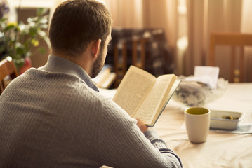 Man reading a book at his home