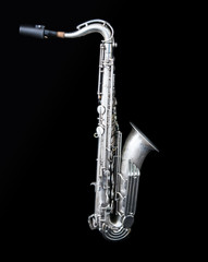 Full view of a silver saxophone standing isolated in black