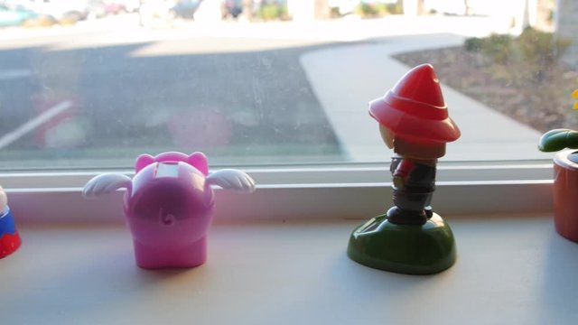 A Dolly Shot Of Bobble Head Figurines In A Window Sill