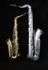 Fototapeta na wymiar Full view of two saxophones standing isolated in black