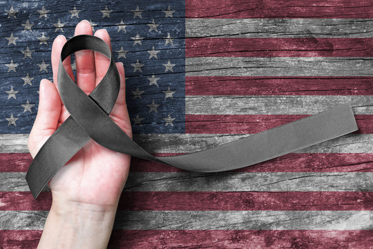 USA United Stated of America 9/11 memorial, Patriot day and National POW/MIA recognition day concept with Black awareness ribbon on people's hand support on American flag