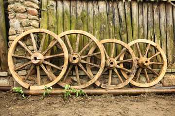 Fototapeta na wymiar Vintage wooden wheels near old fence
