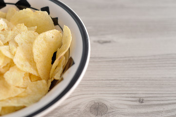 A bowl of crisps on a wooden table