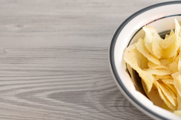 A bowl of crisps on a wooden table