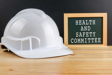 HEALTH AND SAFETY CONCEPT. Personal protective equipment on wooden table over black background with HEALTH AND SAFETY COMMITTEE TEXT - 189706508