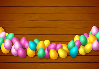 Easter frame with shiny colorful happy eggs spread over wooden background