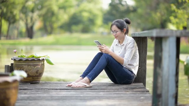 Asian woman sitting beside the lake in the park.