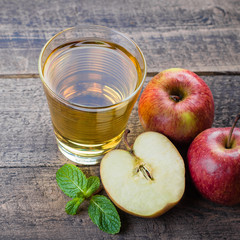 Glass of apple juice with red apples on wooden table background, copy space