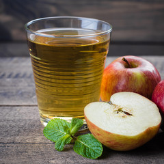 Glass of apple juice with red apples on wooden table background, copy space