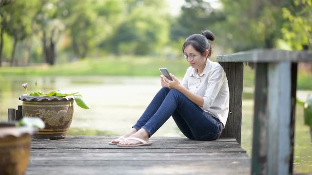 Asian woman sitting beside the lake in the park.