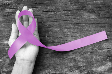 Lavender Ribbon for cancer awareness (all kinds) color splashed on human hand aged wood (bow...