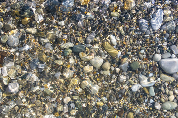 sea pebble beach with multicoloured stones, waves with foam