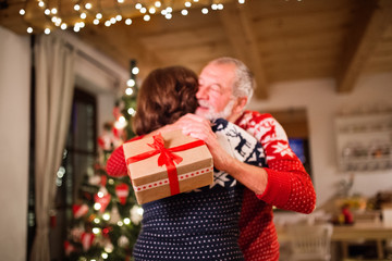Obraz na płótnie Canvas Senior couple exchanging presents at Christmas time.