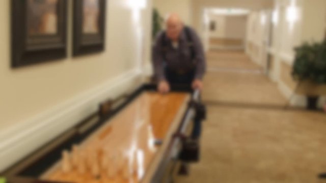 An Older Man Plays Shuffle Board In A Retirement Home