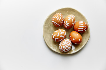 Overhead view of plate with eggs painted various white patterns on Easter holiday. White background, copy space, minimalistic concept