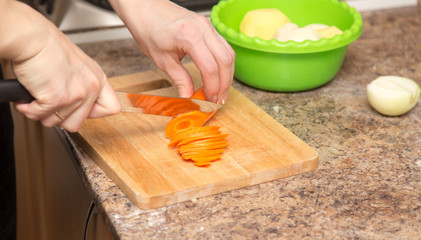 A girl is cutting a carrot with a knife on the board
