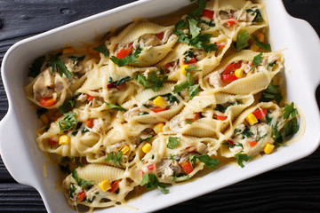 conchiglioni pasta stuffed with chicken, mushrooms and vegetables close-up in a baking dish. Horizontal top view