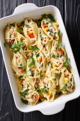 Casserole from conchiglioni pasta stuffed with chicken, mushrooms and vegetables close-up on a table. Vertical top view