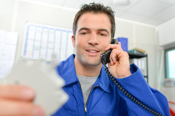 Man in overalls on telephone, holding object