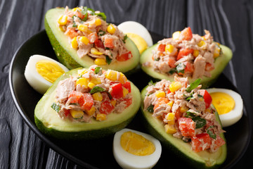 Tasty salad of avocado, tuna, eggs and vegetables close-up on a plate on a table. horizontal