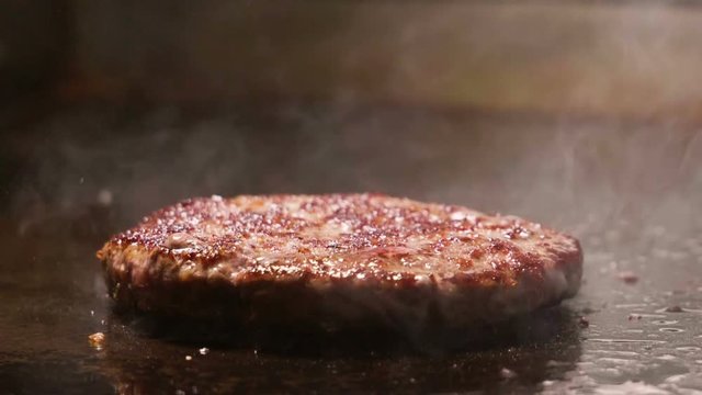 Cooking hamburger. Beef or pork cutlet frying on grill. Slow motion. HD