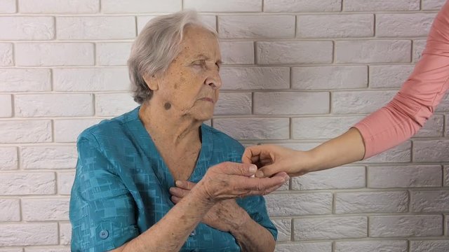 Heart pains. An elderly woman holds her heart.